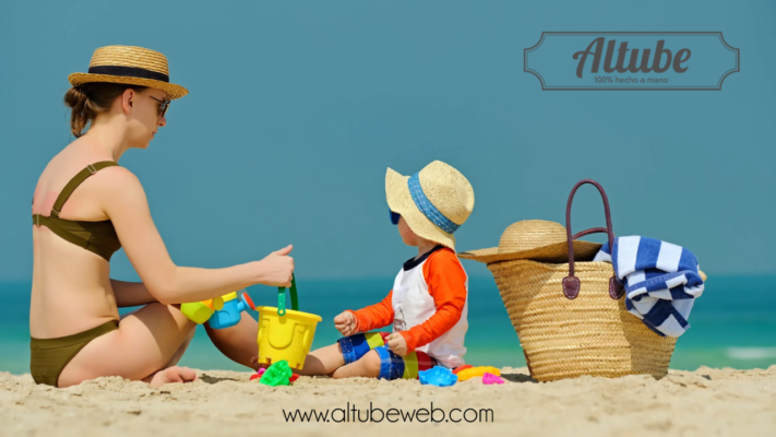 Padres disfrutando de un día de playa con su bebé, utilizando productos personalizados de Altube como mochilas y toallas multi bolsillos